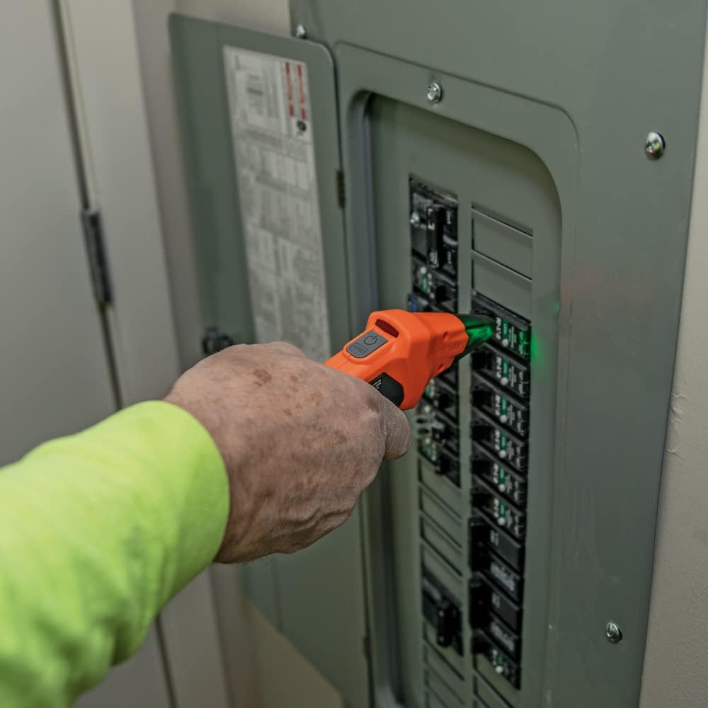 An electrician sweeping the receiver along a row of breakers inside a consumer unit