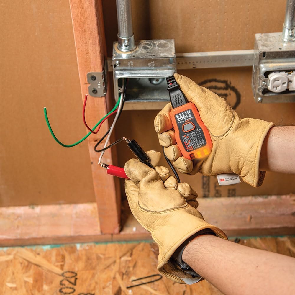 Gloved hands clipping the alligator adapter onto bare conductors at a wall box
